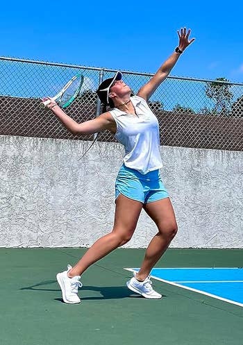 reviewer playing tennis in white top, blue shorts, and white sneakers