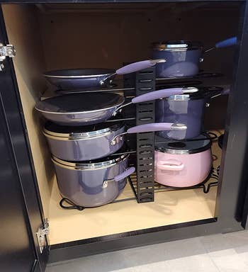 Reviewer image of lavender pots stacked in black pot and pan organizer inside a cabinet 