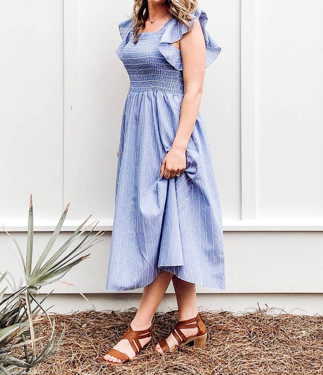 a reviewer wearing a blue midi dress with white pinstripes and short ruffle sleeves 