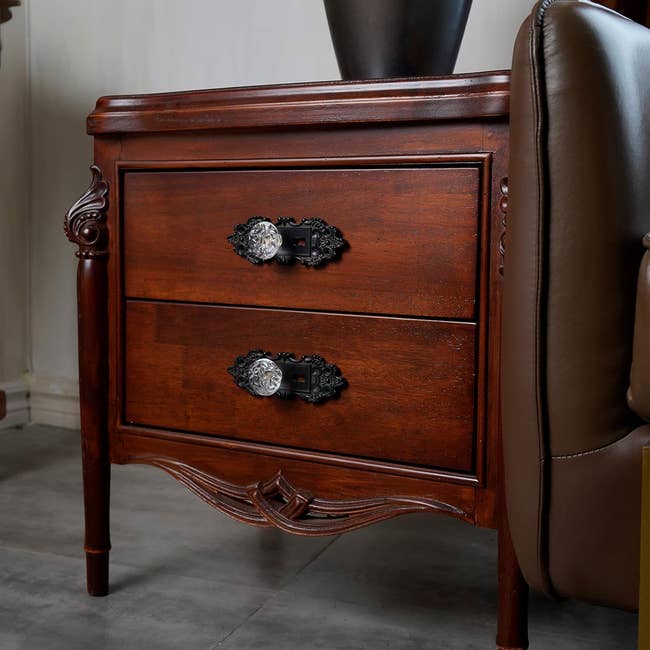 Wooden bedside table with two drawers and ornate handles