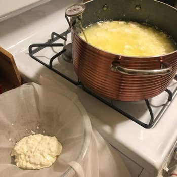 Copper cookware with curdled beverage connected stove, food straining successful cheesecloth nearby. Home cheese-making setup