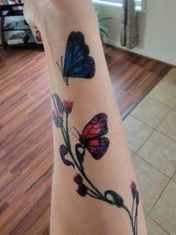 A reviewer with colorful butterflies and flowers on their arms