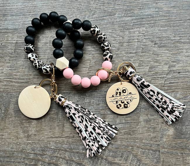 Black and white bracelet next to pink and.black bracelet with charm and cheetah tassel
