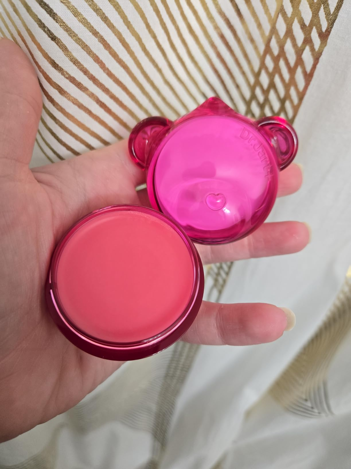 Round pinkish  articulator  balm successful  a manus  with a playful, bear-shaped pinkish  case