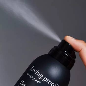 the living proof hair spray being sprayed into the air