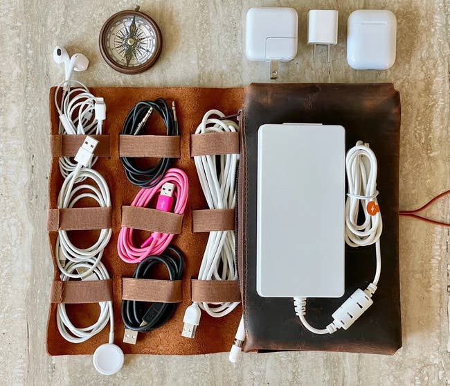the leather electronics organizer holding several cables, earbuds, and a charging port