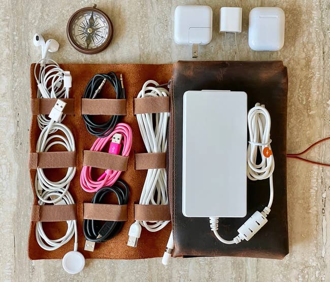 the leather electronics organizer holding respective cables, earbuds, and a charging port