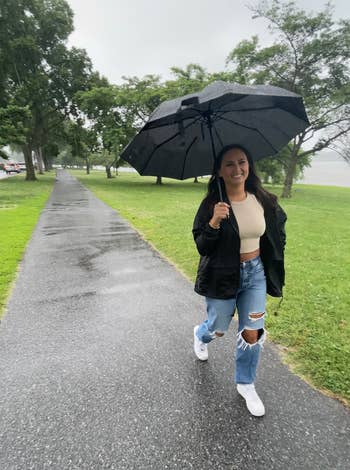 A reviewer wearing the jacket in black while it is raining