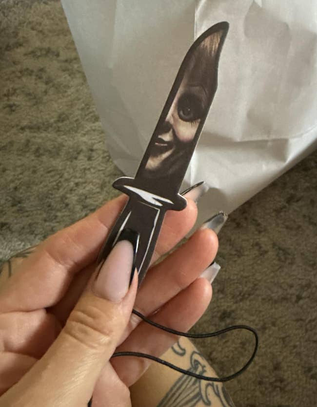reviewer holding a knife-shaped freshener with an oculus design