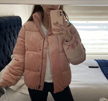 reviewer taking a picture in the mirror wearing the pink velvet coat