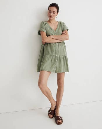 model in the light green button-down mini dress with arms crossed