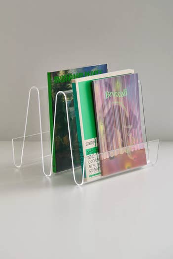 Acrylic book holder displaying colorful books on a shelf; ideal for modern home organization and decor