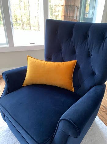 Reviewer's blue armchair with a gold velvet pillow on it