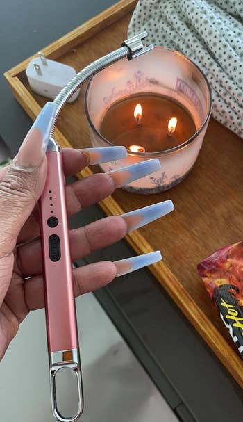 reviewer holds a pink rechargeable lighter near a lit candle