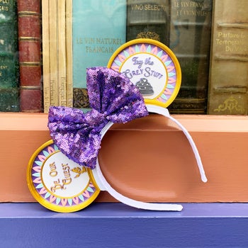 a white headband with a purple bow and beauty and the beast themed ears