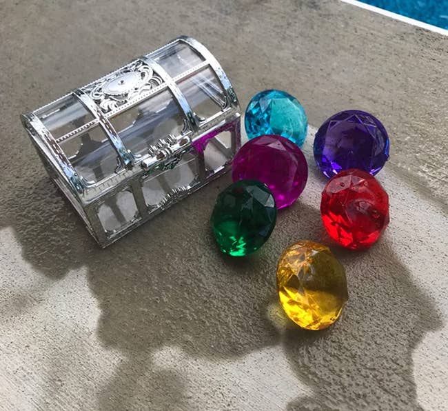 plastic gems next to clear treasure chest 