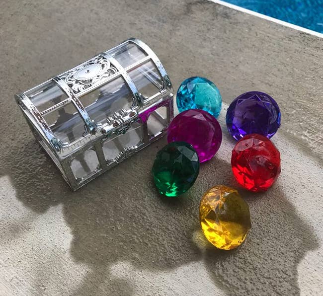 plastic gems next to clear treasure chest 