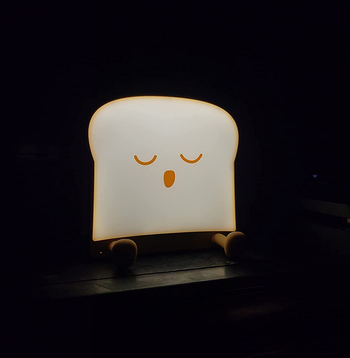 reviewer photo of the sleeping toast night light illuminated in a dark room