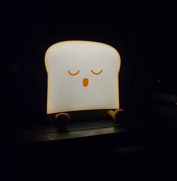reviewer photo of the sleeping toast night light illuminated in a dark room