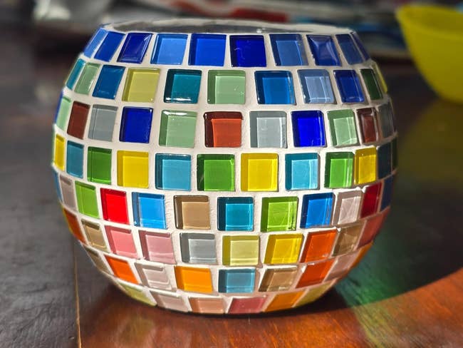 Decorative mosaic vase with multi-colored quadrate solid tiles, shown successful a shopping-focused setting