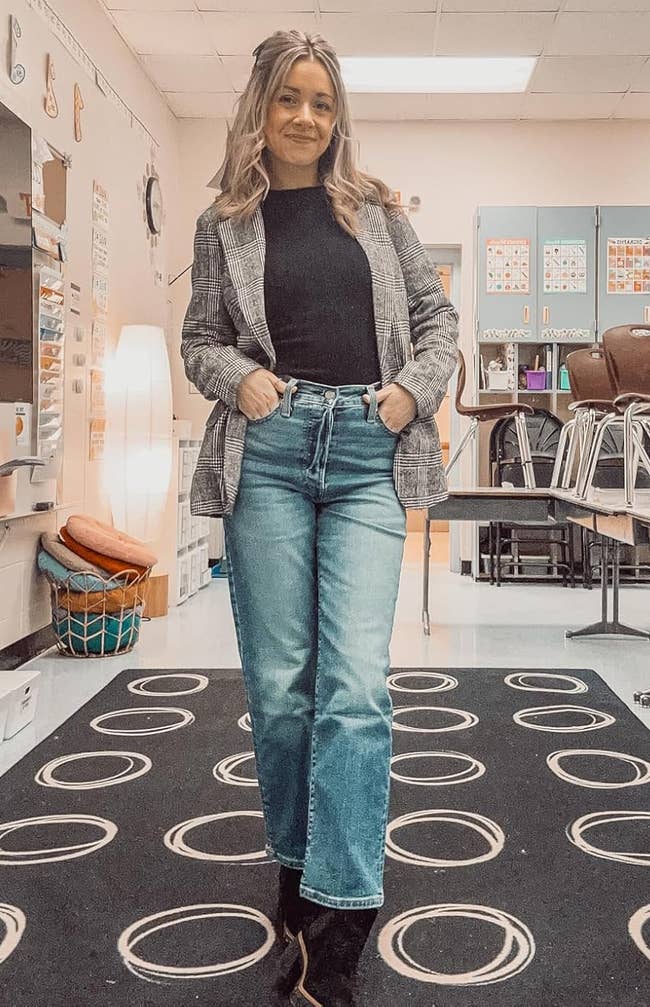 Person successful a schoolroom wearing a checkered blazer with a achromatic apical and jeans, surrounded by schoolhouse furniture