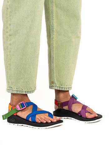Person wearing green pants and multicolored strappy sandals