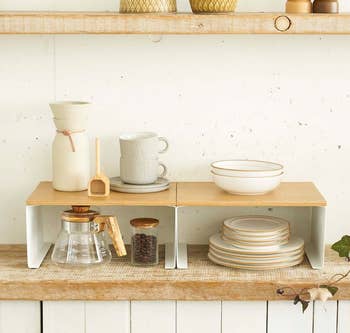 Wooden kitchen shelves with ceramic dishes, a coffee pot, and a jar of coffee beans. Minimalist kitchenware setup for a home shopping article