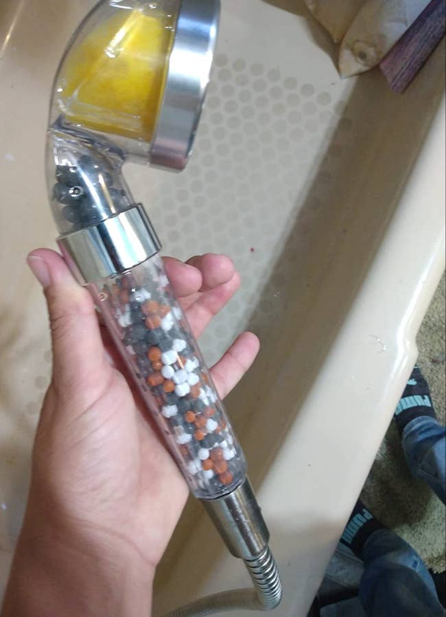 Reviewer holding a showerhead with beads inside the handle and a filter cartridge at the top 