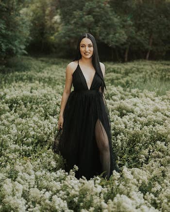 A reviewer in a field of flowers wearing the dress in black 