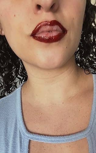 Person with glossy reddish  articulator  liner and airy   lips, wearing a textured bluish  top