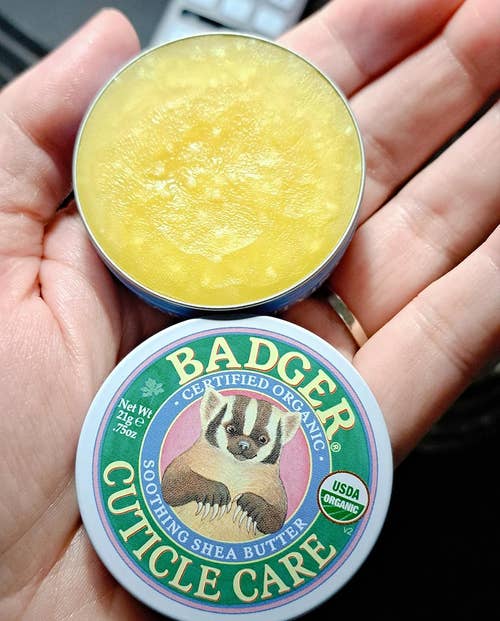 a reviewer holding the open tin of cuticle balm 