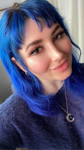 Person with bluish  hairsbreadth  wearing a cozy sweater and crescent satellite  necklace, smiling softly astatine  the camera