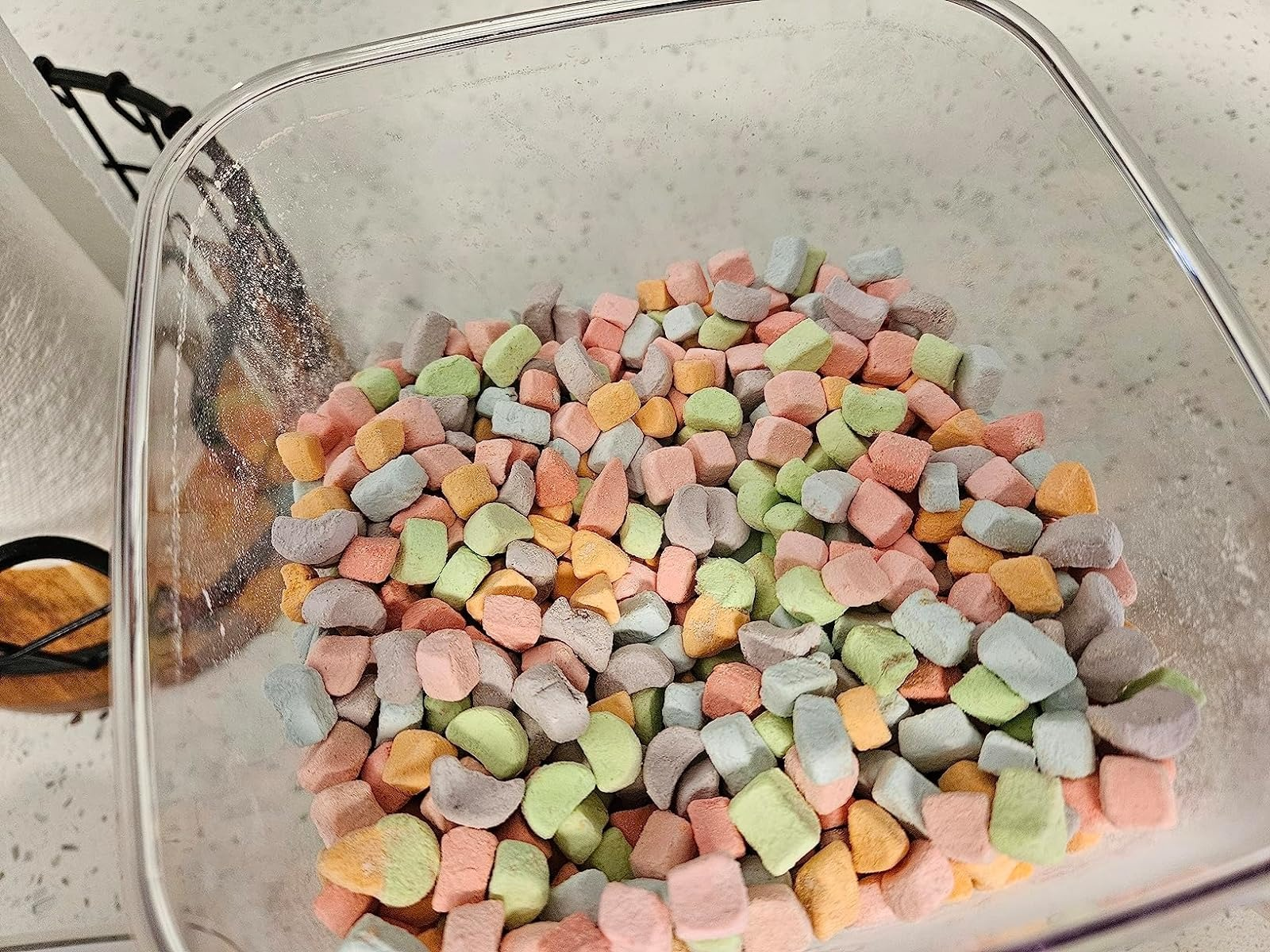A transparent container filled with variously shaped colorful marshmallows