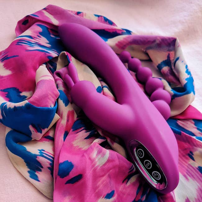 Pink triple-stimulating rabbit vibrator on pink scarf