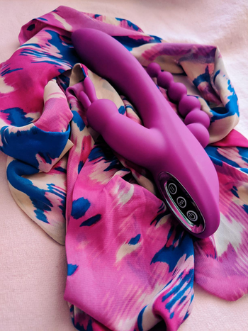 Pink triple-stimulating rabbit vibrator on pink scarf