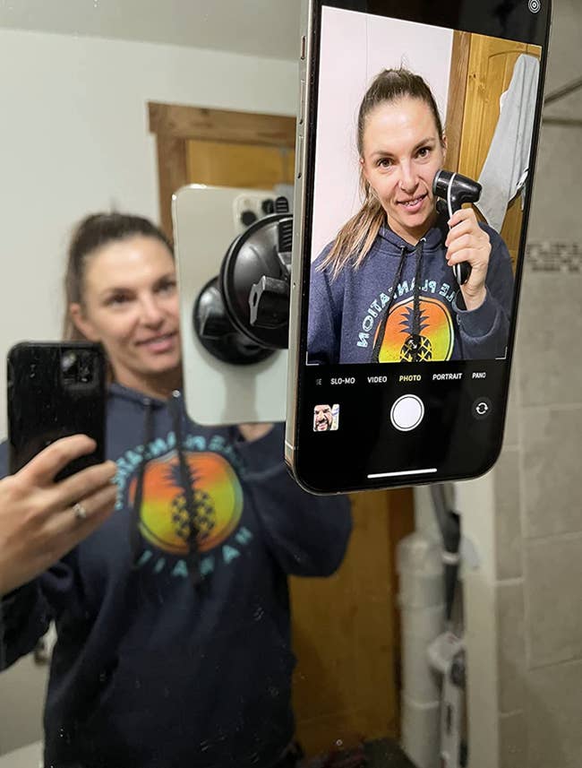 Reviewer filming a skincare tutorial with their phone propped to a mirror 