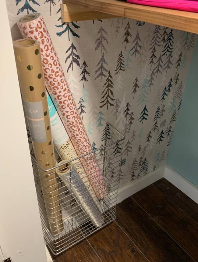 a reviewer photo of the rack installed in a closet holding rolls of wrapping paper 