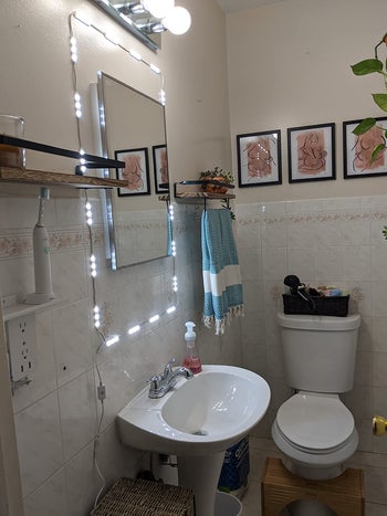 close-up side view of the same lights around rectangle mirror above small sink in decorated bathroom