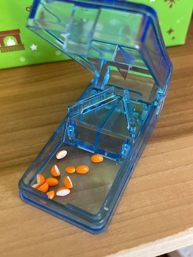 a blue pill cutter with several cut pills inside