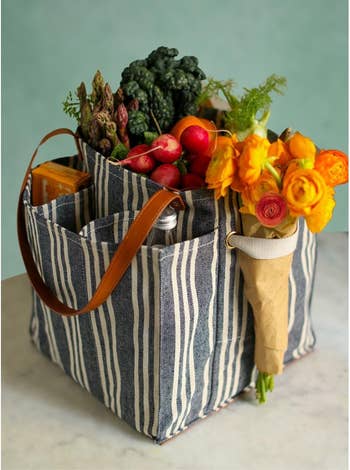 Striped tote container  filled with caller  nutrient   and orangish  flowers, perfect  for buying  oregon  farmers marketplace  trips
