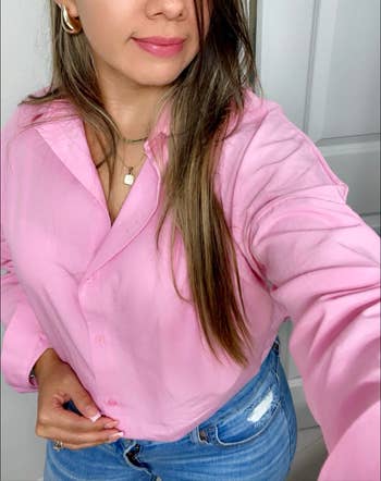 Woman in a pink blouse and blue jeans taking a selfie, focus on outfit, for shopping article