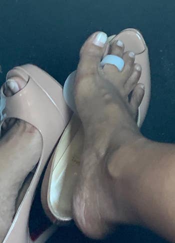 A close-up of a person's feet with one foot stepping out of a beige high-heeled shoe