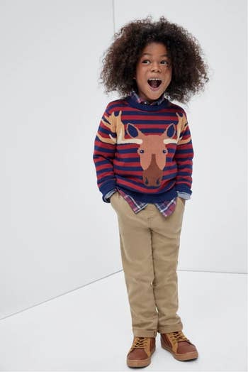 a child wearing a blue and red striped sweater with a cartoon moose
