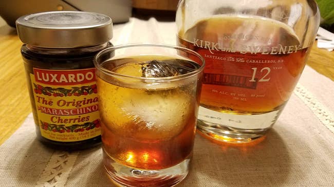 reviewer photo of the jar of cherries, a bottle of alcohol, and an old fashioned with a maraschino cherry in it