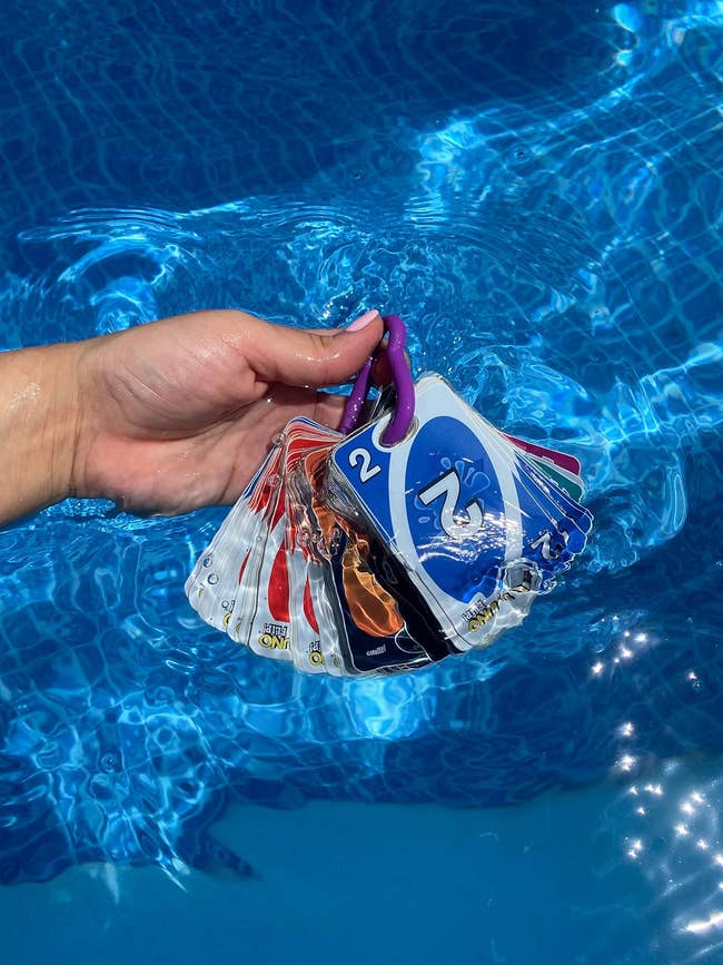 A hand submerging the deck of cards into a pool