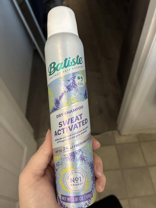 A manus  holds a vessel  of Batiste Sweat Activated Dry Shampoo