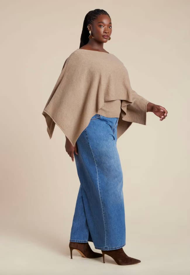 Person wearing a stylish poncho and wide-leg jeans with pointed-toe heels, lasting successful a relaxed pose