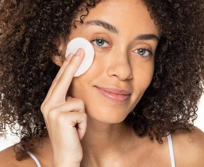 A idiosyncratic mildly applies a fabric pad with waterproof constitution remover to their face