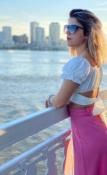 reviewer showing the tie back of the white top with a pink skirt on