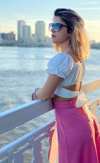 reviewer showing the tie back of the white top with a pink skirt on